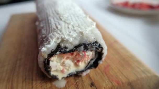 Rollo de sushi grande cubierto con crema en la tabla de cortar — Vídeo de stock
