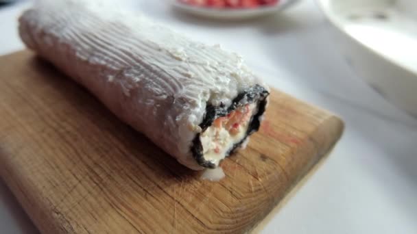 Rollo de sushi grande cubierto con crema blanca en la tabla de cortar — Vídeo de stock