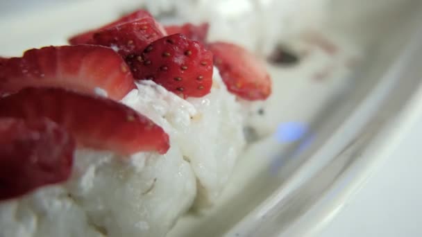 Tangan menempatkan strawberry irisan pada gulungan sushi di atas piring putih — Stok Video