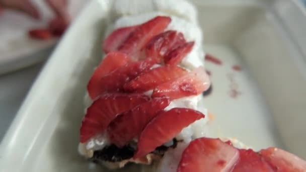 Hand zetten aardbeien plakjes op sushi rollen boven een witte plaat — Stockvideo