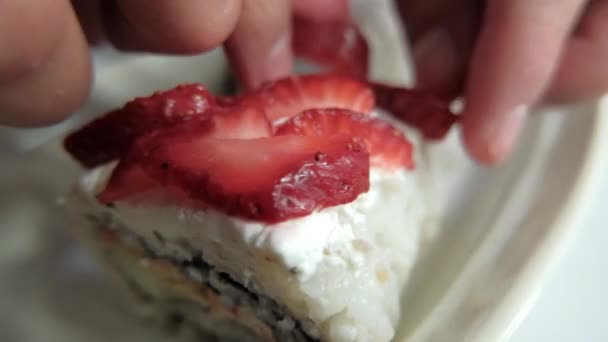 Manos poniendo rodajas de fresa en rollos de sushi encima de un plato blanco — Vídeo de stock
