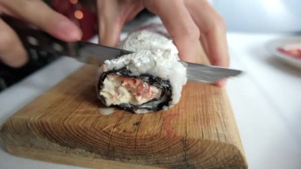 Männliche Hände schneiden große Sushi-Rolle auf einem Schneidebrett — Stockvideo