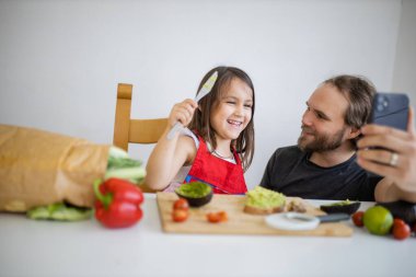 Baba ve kızı avokado yaparken selfie çekiyorlar.