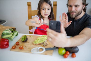 Baba ve kızı avokado keserken selfie çekiyorlar.