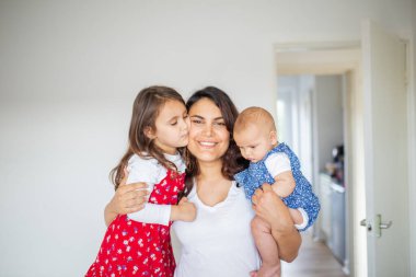 Sevimli genç kızlarını kucaklayan mutlu bir kadın