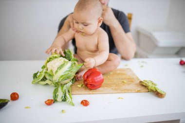 Baba sevgi dolu bir şekilde küçük kızını masanın üstünde tutuyor.