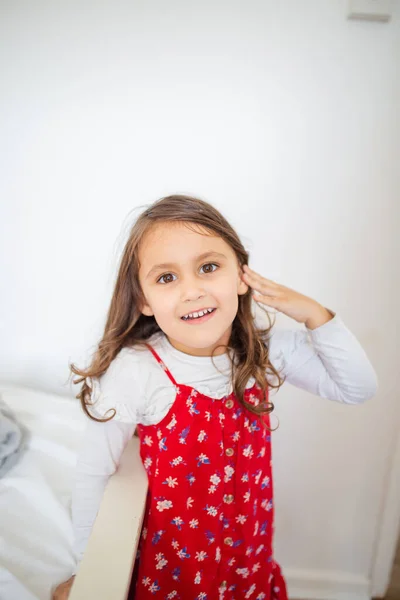 Милая маленькая девочка улыбается и одета в красное платье — стоковое фото
