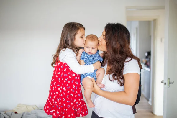 Gelukkig vrouw en een klein meisje houden en zoenen een schattige baby — Stockfoto