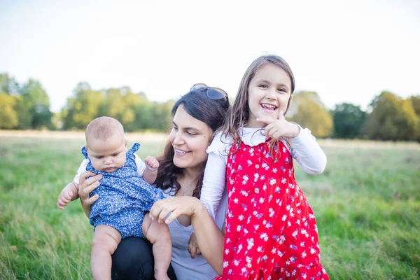 Donna felice e le sue figlie sedute sull'erba — Foto Stock