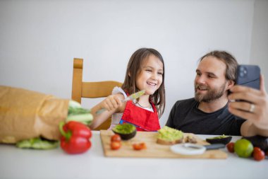 Baba ve kızı avokado yaparken selfie çekiyorlar.
