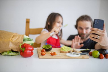 Baba ve kızı avokado yaparken selfie çekiyorlar.