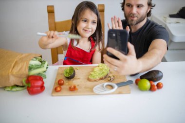 Baba ve kızı avokado yaparken selfie çekiyorlar.