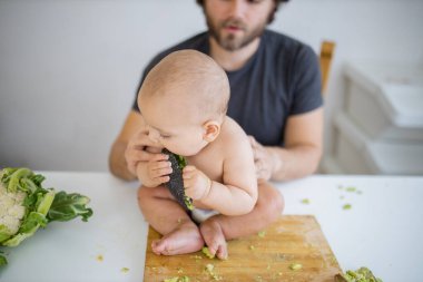 Baba sevgi dolu bir şekilde küçük kızını masanın üstünde tutuyor.