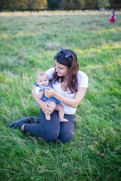 Donna felice seduta sull'erba con il suo bambino — Foto Stock
