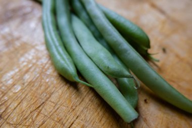 Çizik ahşap bir masada izole edilmiş yeşil fasulyeler.