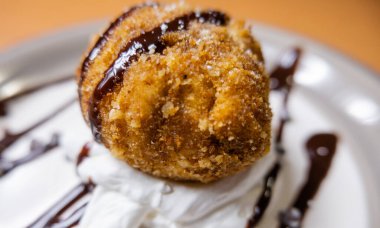 Çikolata soslu ve tabakta kremalı kızarmış dondurma.