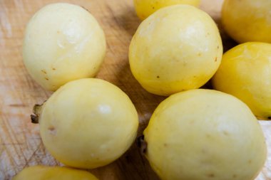 Tahta bir masada taze sarı guavalar.