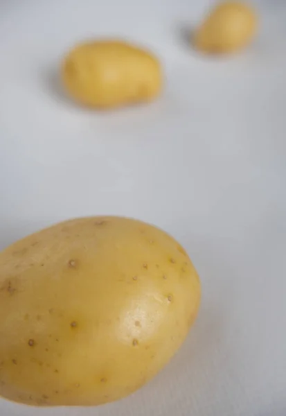 Verse aardappelen geïsoleerd op een witte tafel met wazige achtergrond — Stockfoto