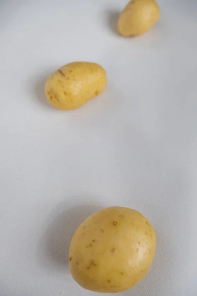 Patatas frescas aisladas sobre una mesa blanca con fondo borroso —  Fotos de Stock
