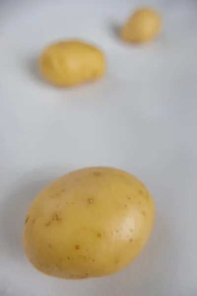 Patate fresche isolate su un tavolo bianco con sfondo sfocato — Foto Stock