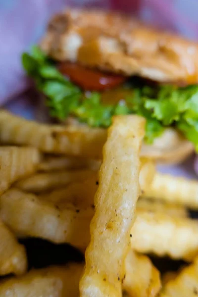 Close-up of french fries and hamburger on paper — Stock Photo, Image