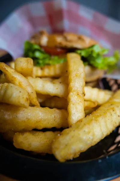 Close-up of french fries and hamburger in black basket — Stock Photo, Image