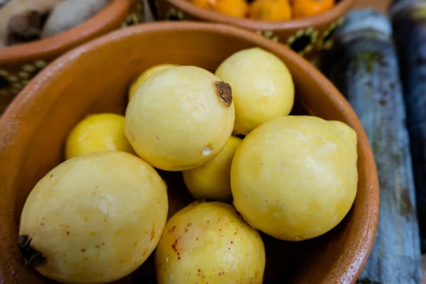 Verse guaves en meidoorns in kommen van klei naast suikerriet — Stockfoto