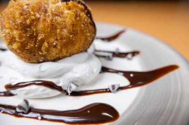 Çikolata soslu ve tabakta kremalı kızarmış dondurma.