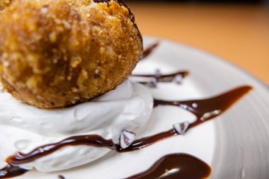 Çikolata soslu ve tabakta kremalı kızarmış dondurma.