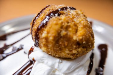 Çikolata soslu ve tabakta kremalı kızarmış dondurma.