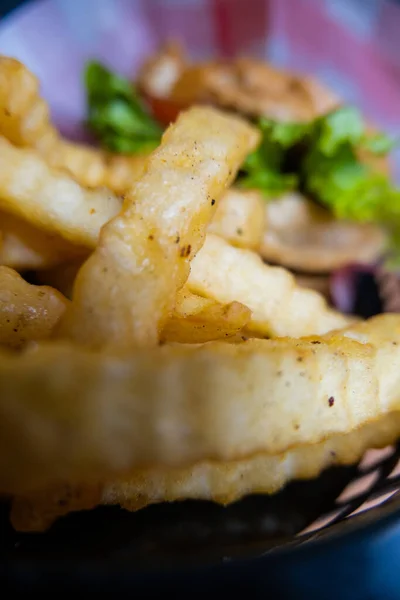 Close-up of french fries and hamburger in black basket — Stock Photo, Image