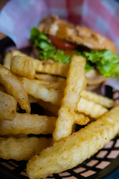 Close-up of french fries and hamburger in black basket — Stock Photo, Image