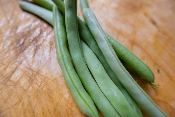 Grüne Bohnen isoliert auf einem zerkratzten Holztisch — Stockfoto