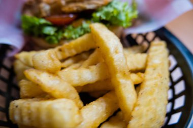 Yukarıdan siyah bir sepetin içinde patates ve hamburger.