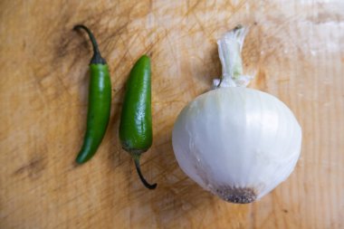 Taze biber ve soğan ahşap bir masada izole edilmiş.