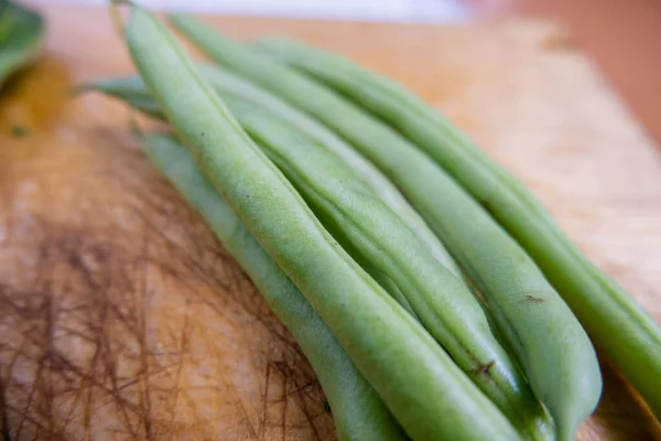 Green beans isolated on a scratched wooden table — Stock Photo, Image