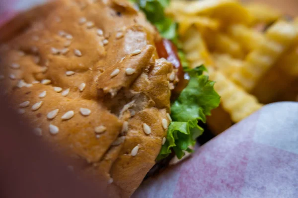 Close-up of hamburger and fries on white paper — Stock Photo, Image