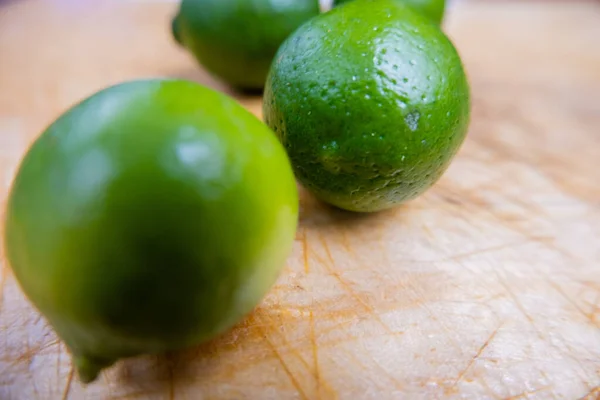 Limes fraîches isolées sur une table en bois rayé — Photo