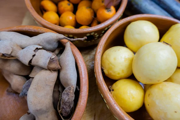 Fresh guavas, hawthorns, and tamarind in clay bowls — Stock Photo, Image