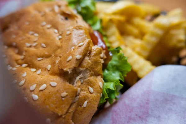 Detailní záběr hamburgeru a hranolek na bílém papíru — Stock fotografie