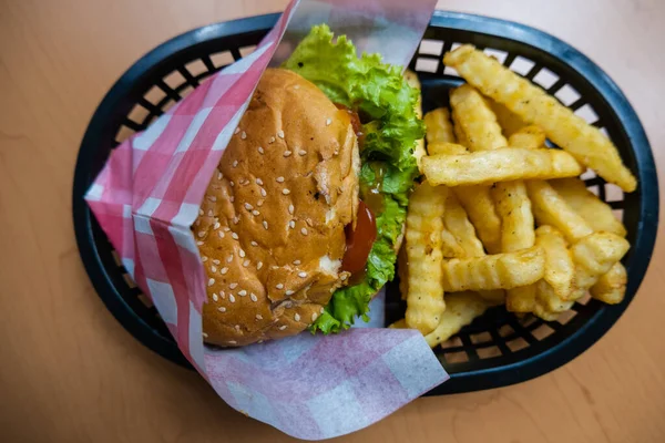 Hamburger and fries on a black basket from above — Stock Photo, Image
