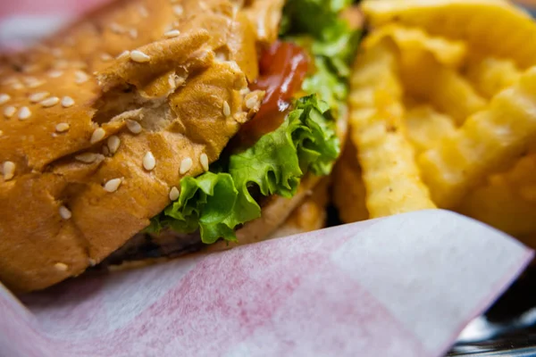 Close-up of hamburger and fries on white paper — Stock Photo, Image