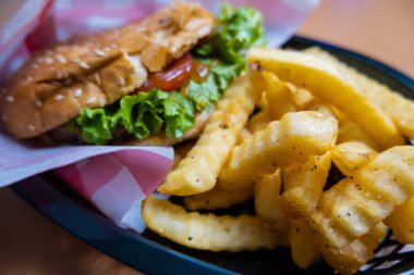 Yukarıdan siyah bir sepetin içinde patates ve hamburger.