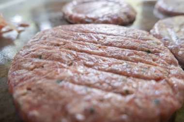 Büyük bir tavada kızarmış hamburger eti.