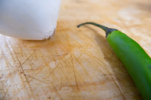 Friss chili paprika és hagyma izolálva egy fa asztalon — Stock Fotó