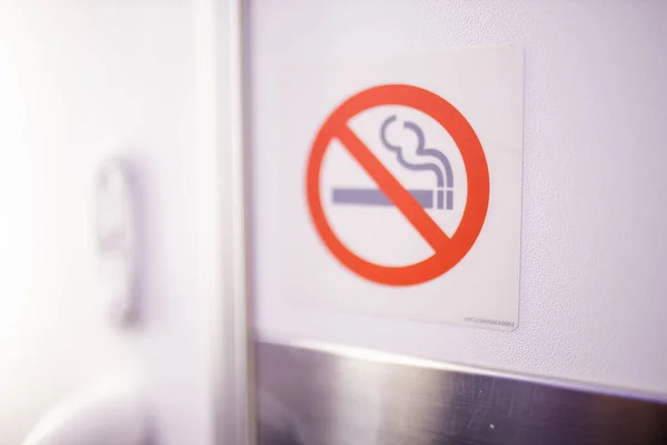No smoking sign on white surface inside an airplane