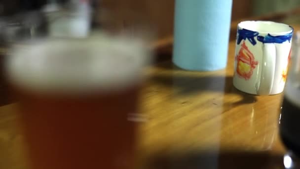 Segelas bir di atas meja kayu dengan latar belakang kabur — Stok Video
