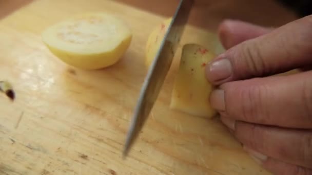 Mãos cuidadosamente cortando goiabas acima de uma tábua de corte — Vídeo de Stock