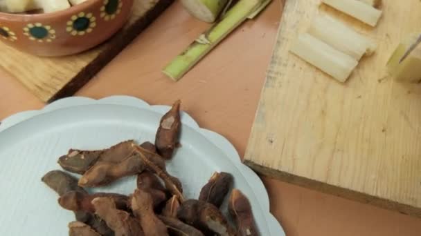 Kézzel szeletelt cukornád a vágódeszkán mellett egy lemez tamarinds — Stock videók