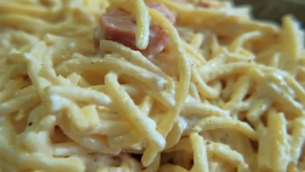 Witte saus spaghetti met ham plakjes op een bord — Stockvideo